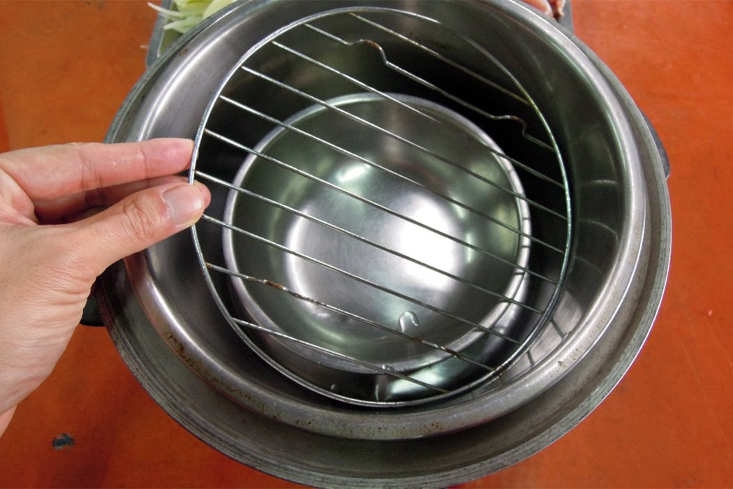 傳統電鍋內鍋中多放一小碗（碗中先放參片）與層架，承接雞精。