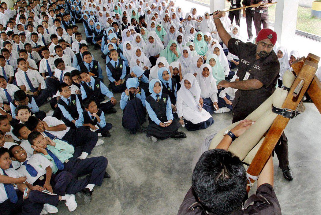 鞭刑是否能有效地製止犯罪？圖為2004年馬來西亞警員對國小生展示如何對罪犯施予鞭刑。 圖／美聯社