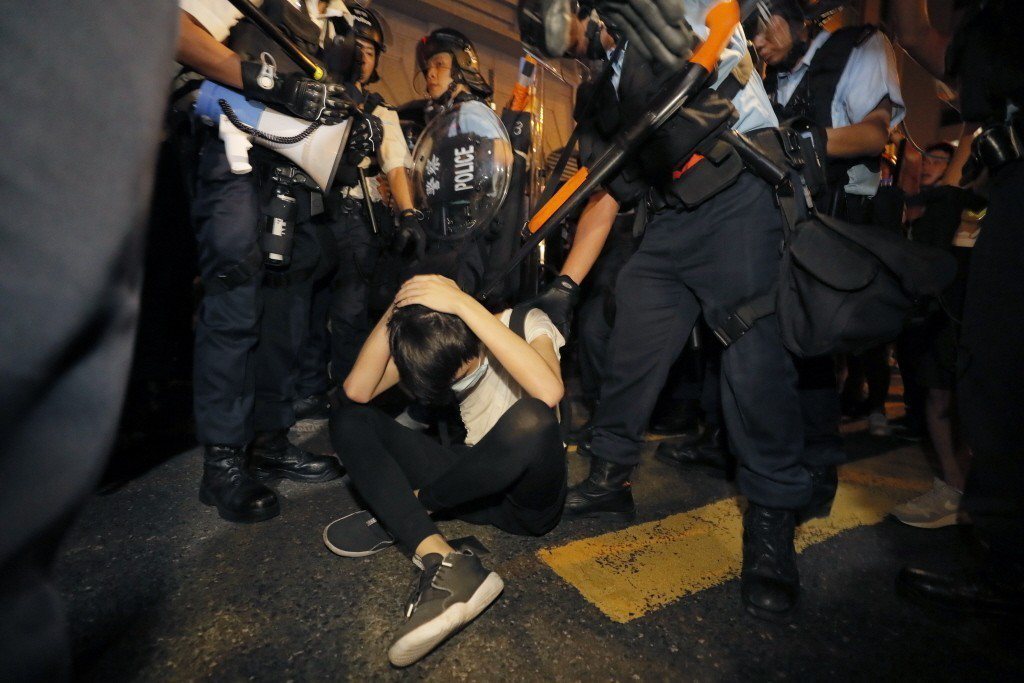 一名反送中示威者坐地以手保護頭部避免遭港警攻擊致傷。 圖／美聯社