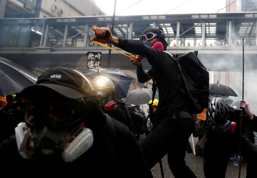 一名香港示威者以彈弓反制警方攻勢。 圖／路透社