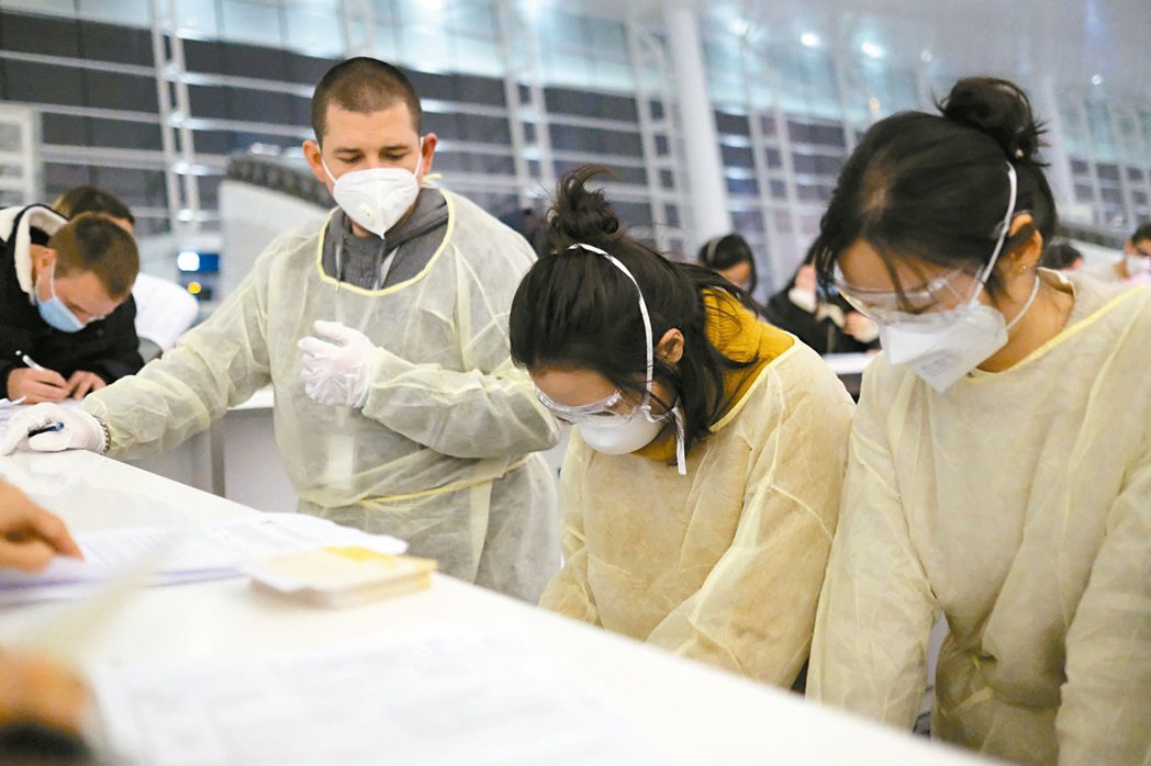 圖為戴口罩的旅客在武漢國際機場填寫文件。 美聯社