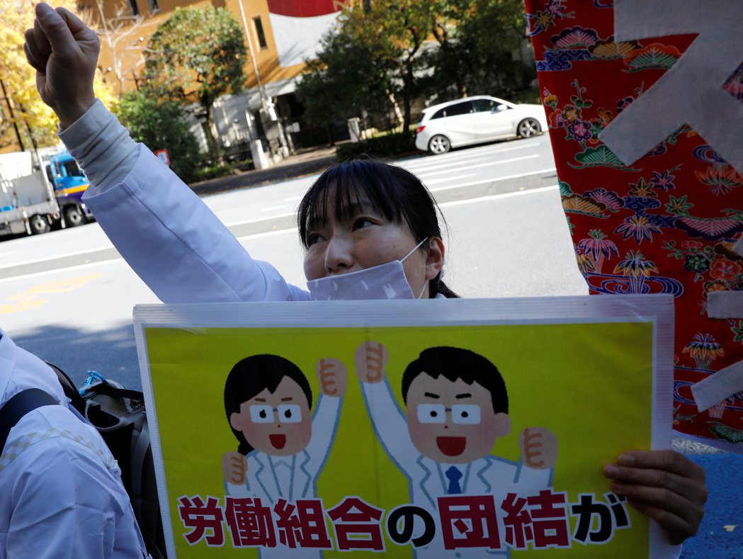 圖為12月4日的東京，民眾戴著口罩高呼口號，支持醫院裡的醫療人員罷工。  圖...
