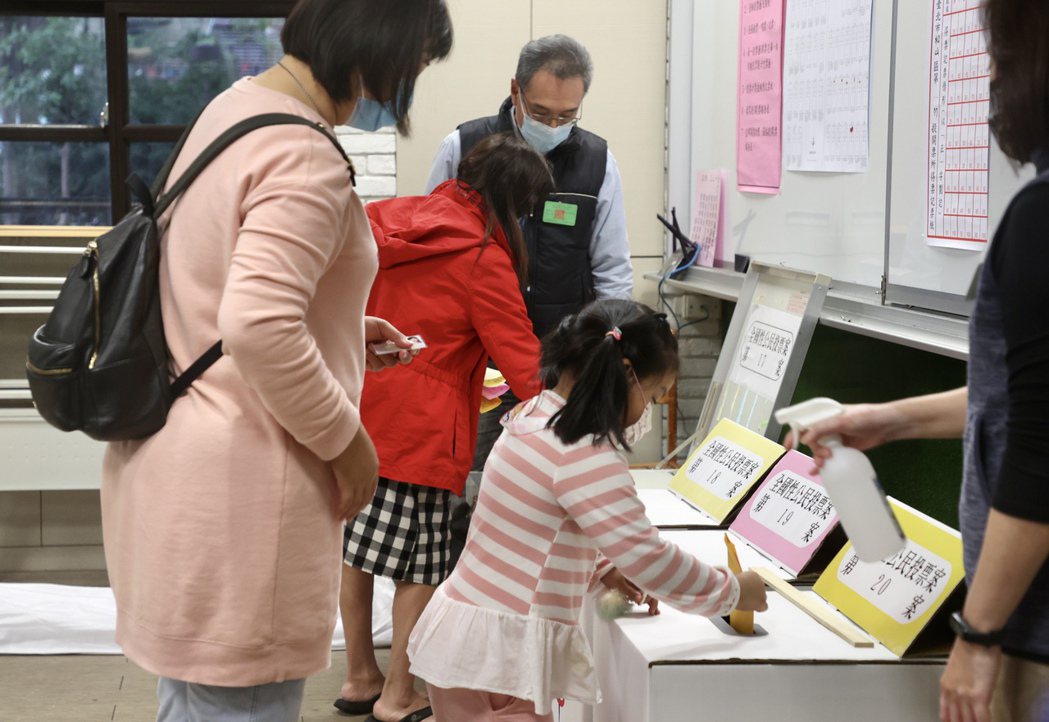 本次四項公投首度開放六歲以下兒童進投票所，小女孩幫媽媽將選票投入票櫃，見證民主歷程。 圖／聯合報系資料照片