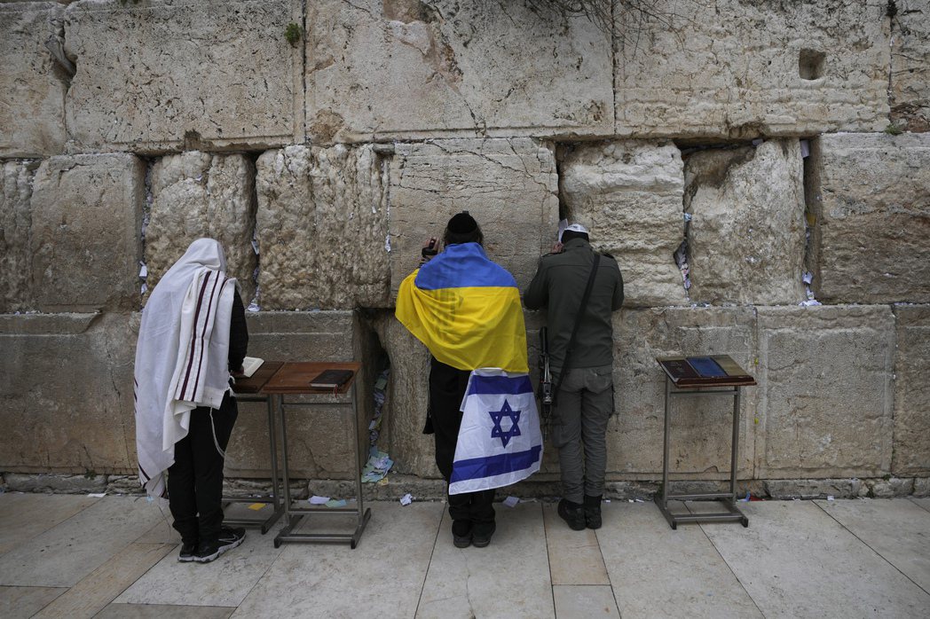 一名身披烏克蘭和以色列國旗的猶太男子在西牆祈禱。 圖／美聯社