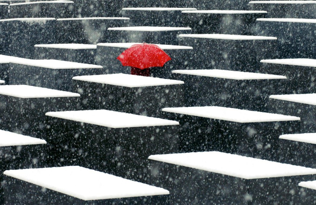  圖為2005年的雪季，一名男子撐著紅傘走進柏林的歐洲被害猶太人紀念碑。 圖／美...