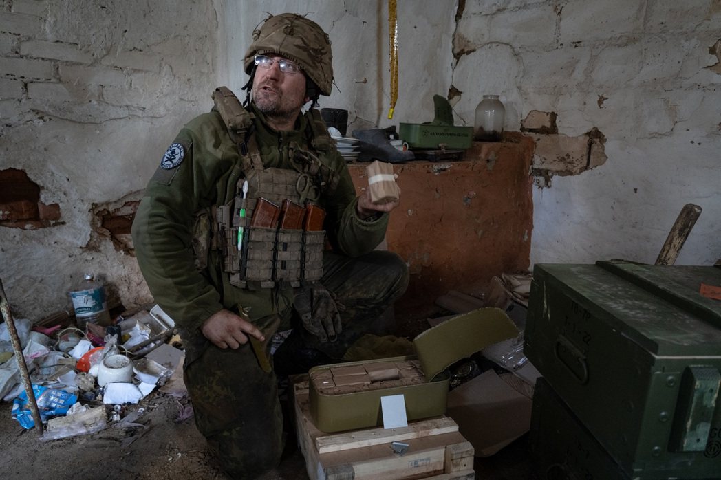 一名烏克蘭士兵從鐵盒中取出用紙包著的子彈。 攝影／陳彥婷
