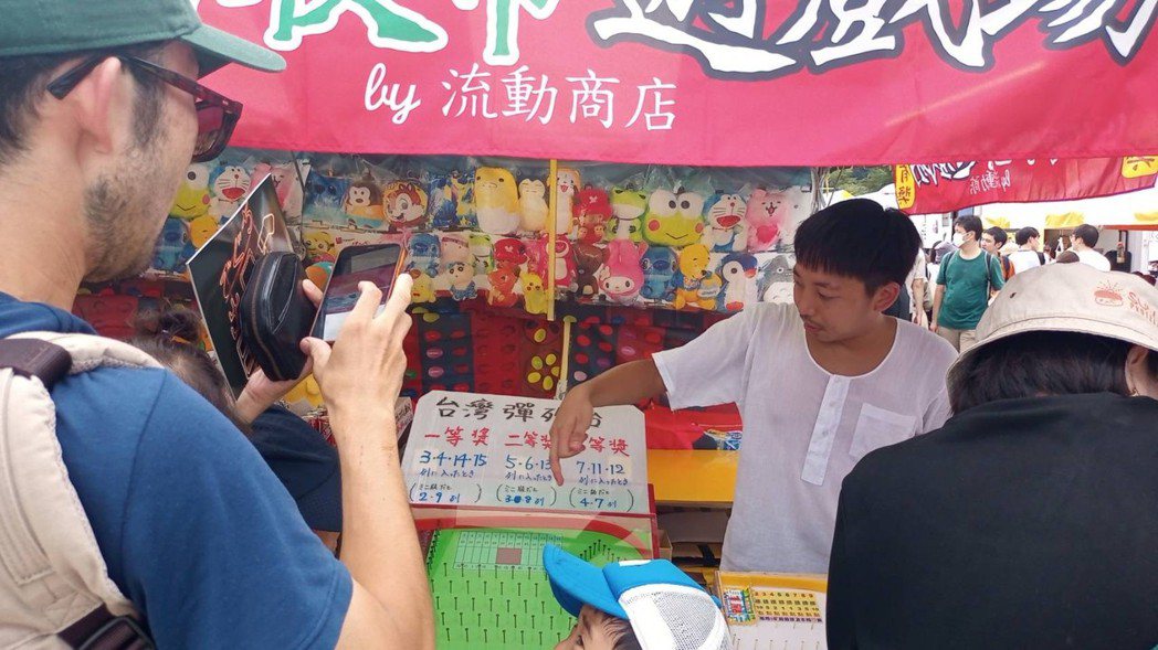 三文字昌也穿著經典的台灣汗衫，向日本顧客介紹彈珠台玩法。 圖／三文字昌也提供