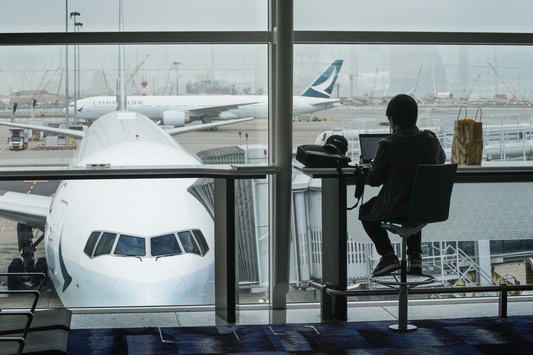 香港國際機場的等候旅客和停機坪上的國泰航空飛機。 圖／美聯社