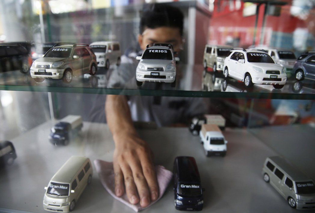 印尼雅加達一家大發汽車展售場的人員，正在擦拭汽車模型櫥窗。 圖／路透社