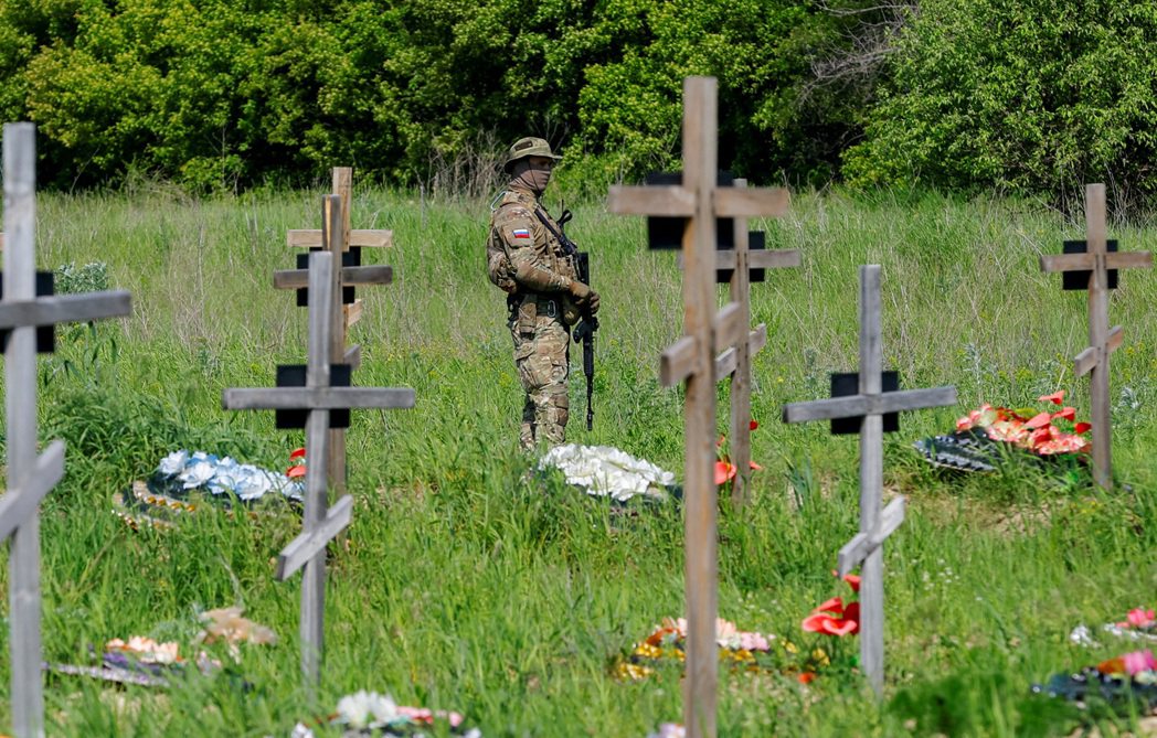 俄軍在盧甘斯克的控制區，一名武裝士兵看守鎮亡俄軍的墳墓。 圖／路透社
