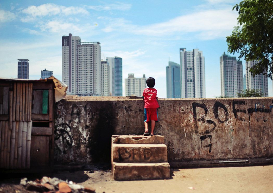 圖為 2014 年，一位小孩在貧民窟玩到一半時停下來欣賞雅加達的城市天際線。...