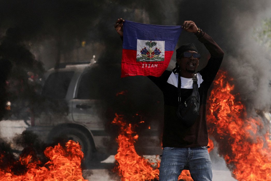2024年3月1日，海地太子港，一名示威者在抗議總理亨利政府和不安全局勢時舉起海...