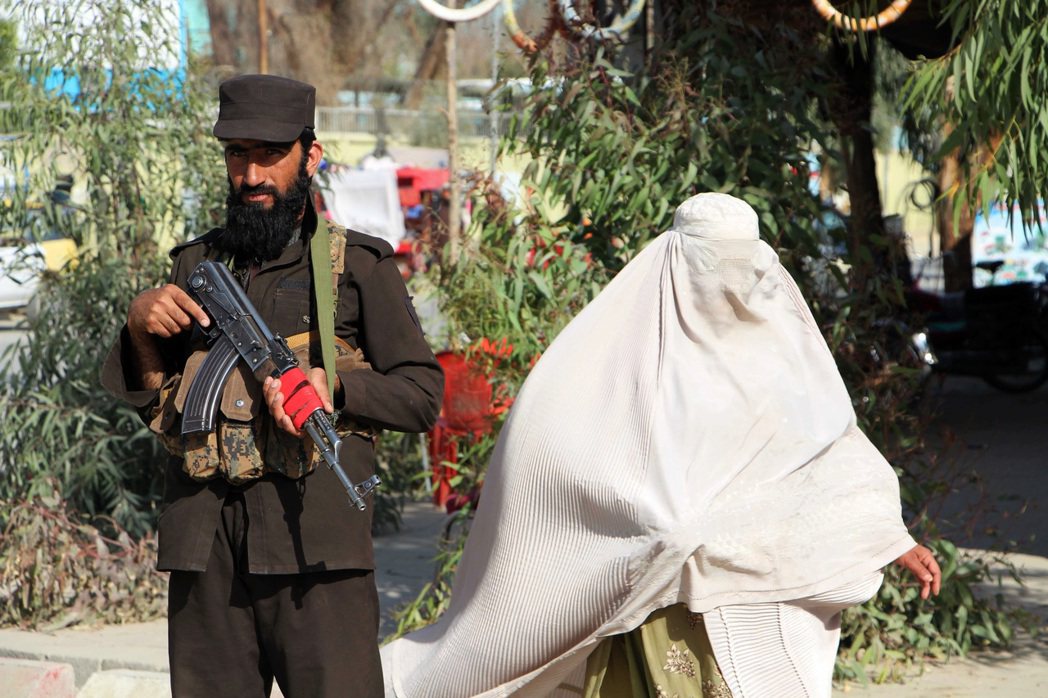 阿富汗街頭的婦女經過塔利班士兵身邊。 圖／歐新社