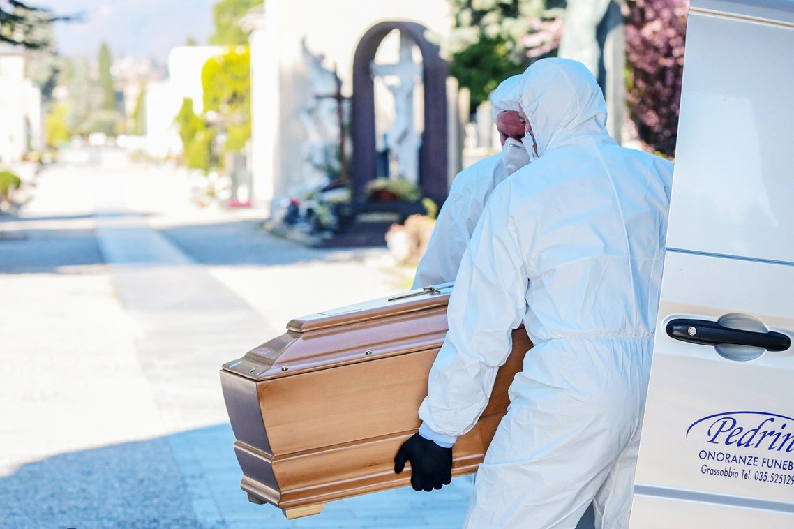 圖為義大利倫巴底區的殯葬業者穿戴口罩與防護衣，將病逝的肺炎患者的棺木抬下車。 圖...
