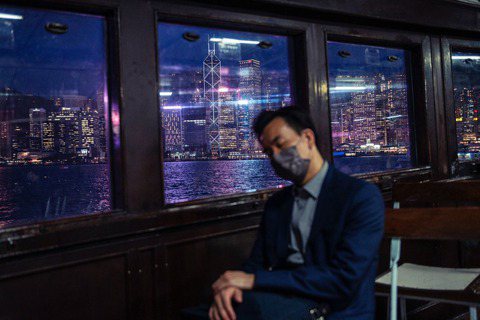 2022 年，一名男子在天星小輪上打盹，往窗外望去是香港的夜景。 圖／美聯社