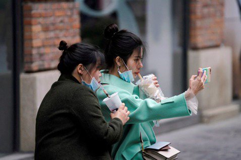 2名在武漢街頭喝奶茶的中國女性。 圖／路透社