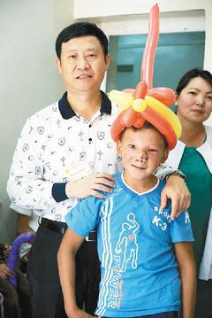 納葛立罹患罕見的顱顏裂，害羞的他和為他手術的台灣醫師羅綸洲合照。 圖／羅慧夫基金會提供