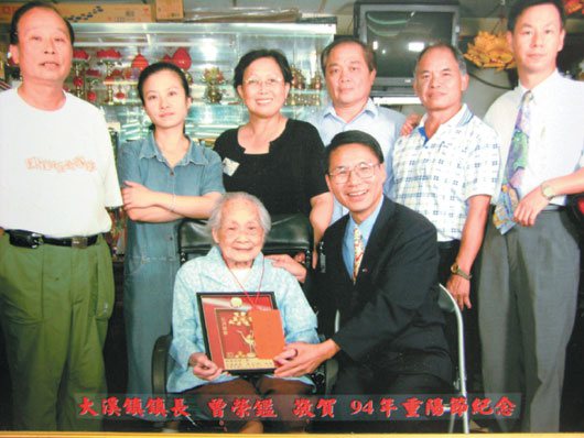 108歲林李也好是大溪鎮最長壽的人瑞，這張照片是民國94年、她103歲時，前任大溪鎮長曾榮鑑賀節照片。 記者劉愛生 翻攝