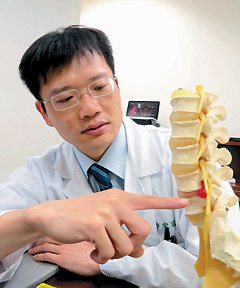 醫師宋冠嶔指出，年輕人玩３Ｃ產品姿勢不對，就可能造成椎間盤突出（紅色部分）。
記者周宗禎／攝影