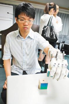 28歲的邱傑使用專利輔具「動態手功能訓練器」進行復健，手部活動功能明顯獲改善。 記者胡蓬生／攝影