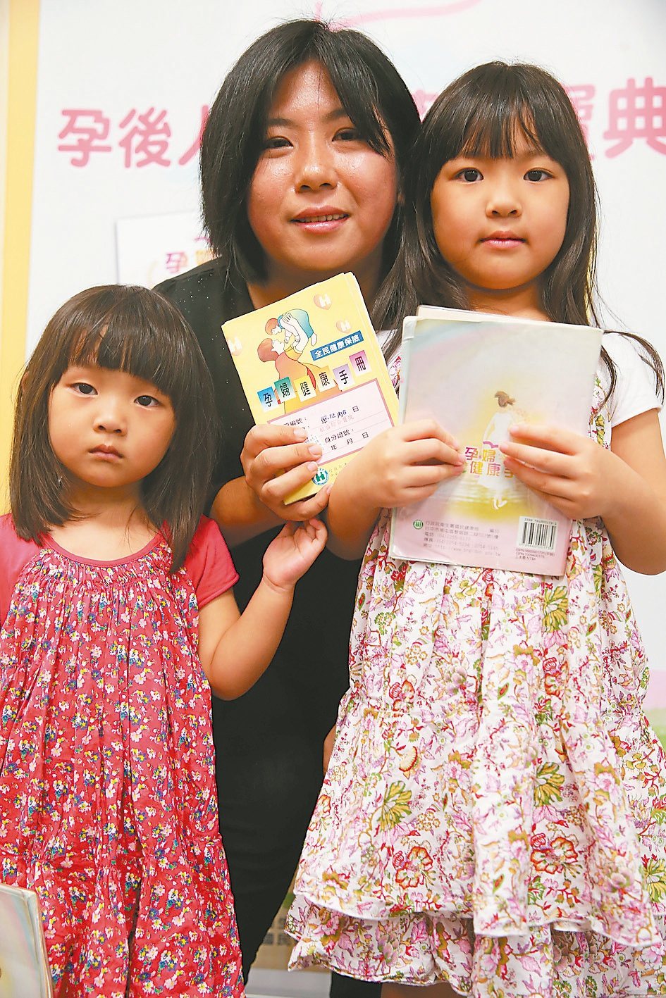育有四個小孩的龐國詩（中）拿過四種版本「孕婦健康手冊」，她和兩個女兒昨天稱讚新版手冊內容豐富。
