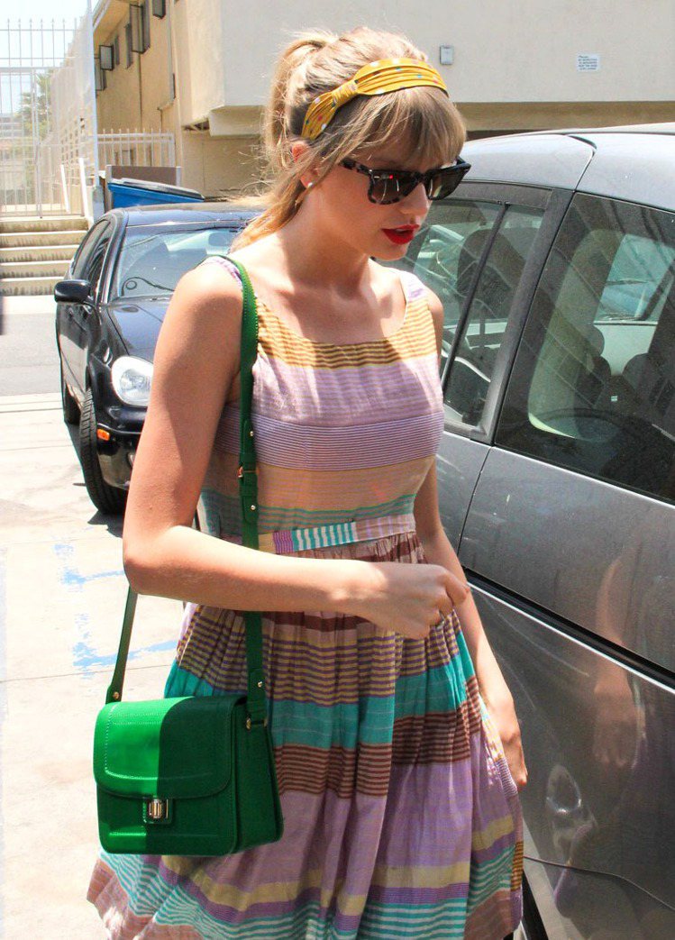 泰勒絲揹Elie Saab飽合綠方包，搭配條紋洋裝和黃色髮帶，用繽紛的色系展現夏...