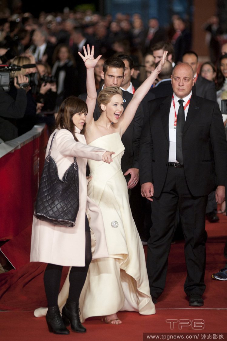 在羅馬《飢餓遊戲 2：星火燎原》首映會中，珍妮佛勞倫斯忙著跟影迷打招呼，大動作舉起雙手完全不顧身上那件 Dior 禮服會往下滑，十足帥氣女風格。圖／達志影像