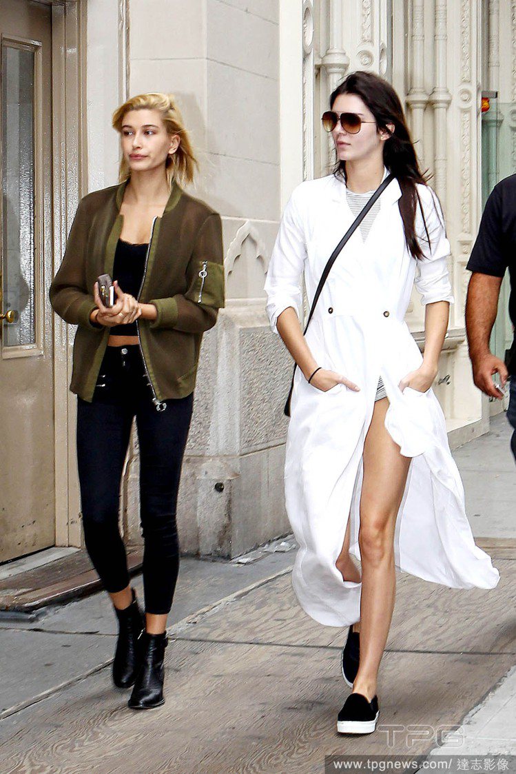 Kendall Jenner以一身白色長風衣搭配灰色素T與短褲瀟灑上街，黑色休閒...