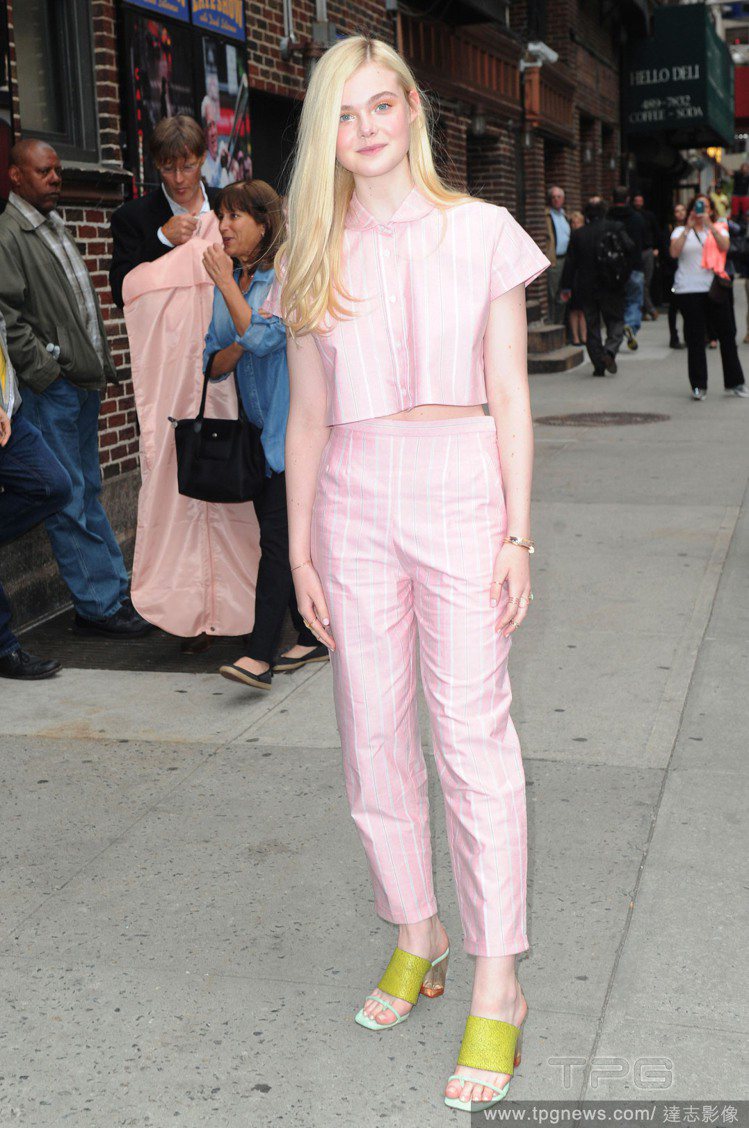 艾兒芬妮（Elle Fanning）身穿粉紅條紋棒球套裝，短版上衣和高腰褲的組合簡約又俏皮，粉嫩的色彩搭配芥末黃涼鞋實在亮眼極了！圖／達志影像