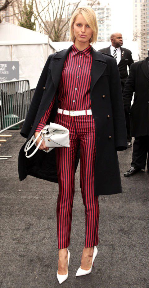 Karolina Kurkova穿著Michael Kors紅底黑條紋連身褲裝，搭配尖頭鞋的極簡都會風，披上黑色大衣，散發出「大哥的女人」的時尚氣勢。圖／達志影像