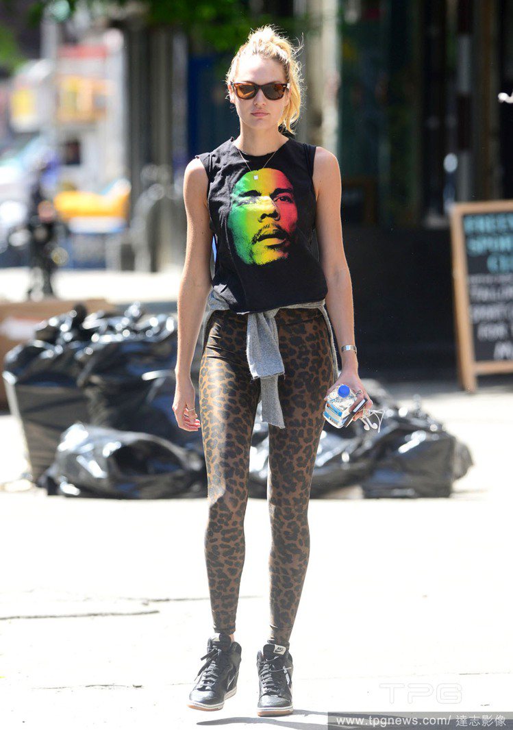維多利亞的秘密超模 Candice Swanepoel 將豹紋內搭褲搭配黑底彩色肖像背心，時髦街頭風再搭被率性地將外套綁在腰間，巧妙修飾下身並且呼應流行風潮。圖／達志影像