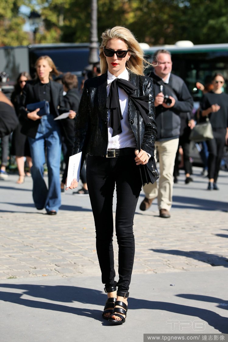 時尚編輯 Joanna Hillman 的黑色褲裝套裝很有 YSL 的浪漫搖滾風，蝴蝶結與蛇紋外套的組合，混搭出另類的個性味。圖／達志影像