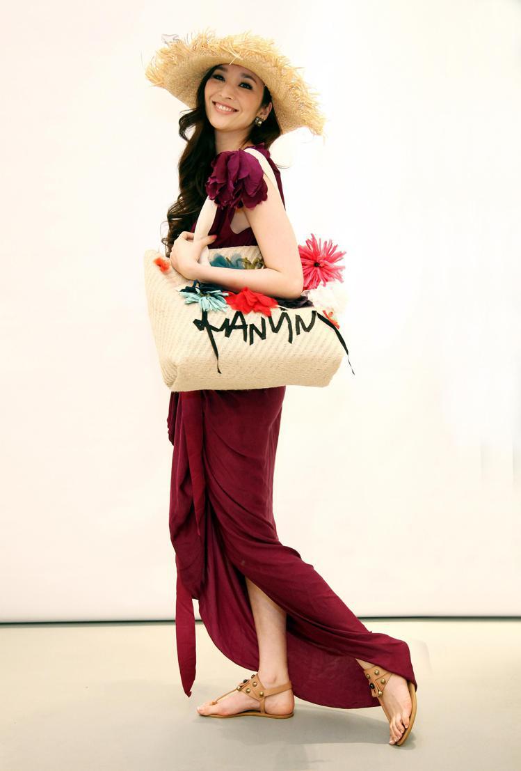 吳佩慈穿Lanvin紫紅色禮服配草帽，背上度假風托特包，有股華麗悠閒的南洋風格。圖／Lanvin提供