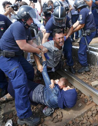 難民從匈牙利收容營逃跑遭阻擋，婦女抱著幼兒摔倒在鐵軌。 （路透）