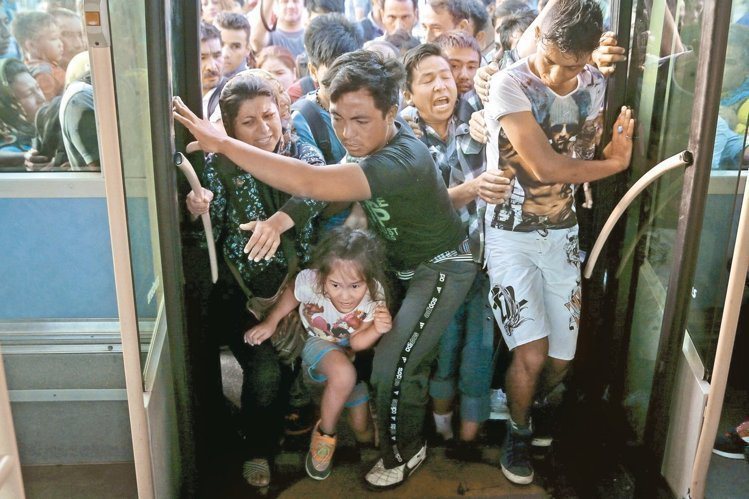 搭乘客輪抵達希臘比雷埃夫斯港的難民，七日爭先恐後搶搭巴士。 路透