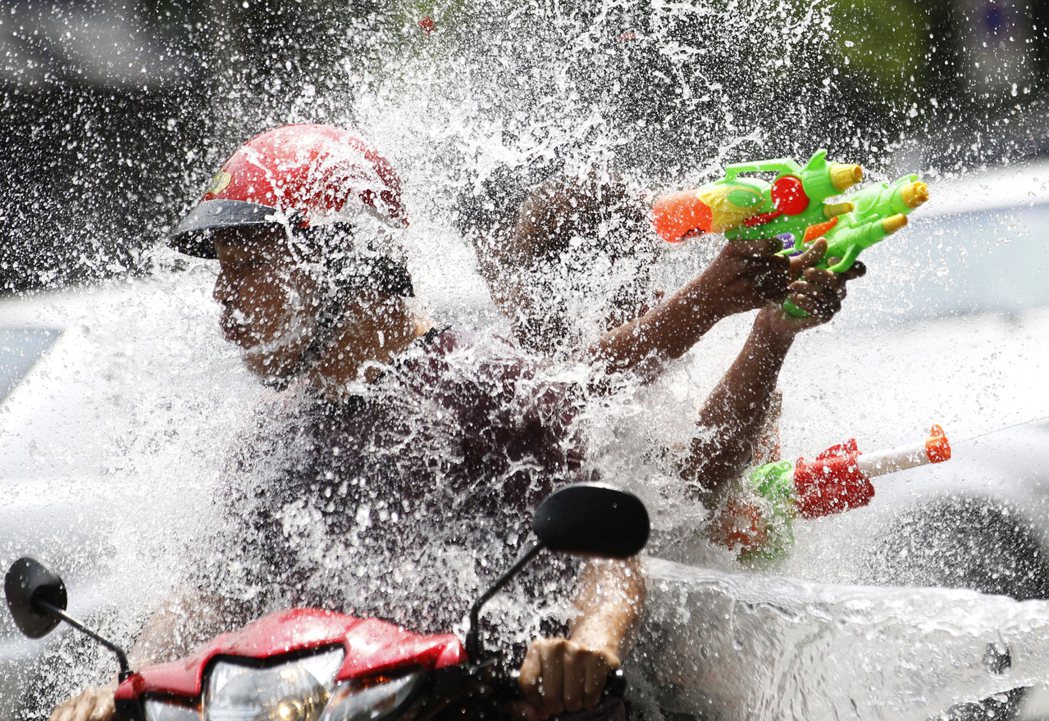 4月12日：潑水節日前夕，曼谷街頭的機車騎士已與路人先行潑水慶祝。 圖／美聯社