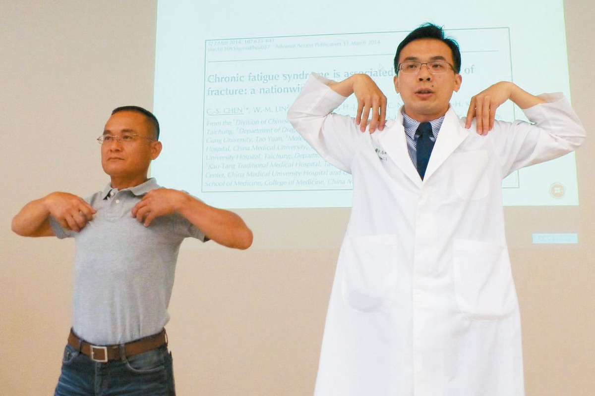 中醫師陳志昇(右)教導王姓水電行老闆(左)透過擴胸運動，鬆動筋膜紓壓。