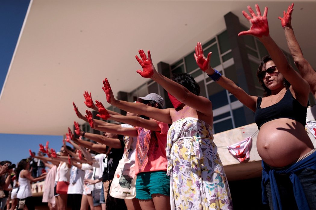 示威者將雙手染成紅色，象徵女性在巴西社會中所承受的性別暴力。 圖／路透社