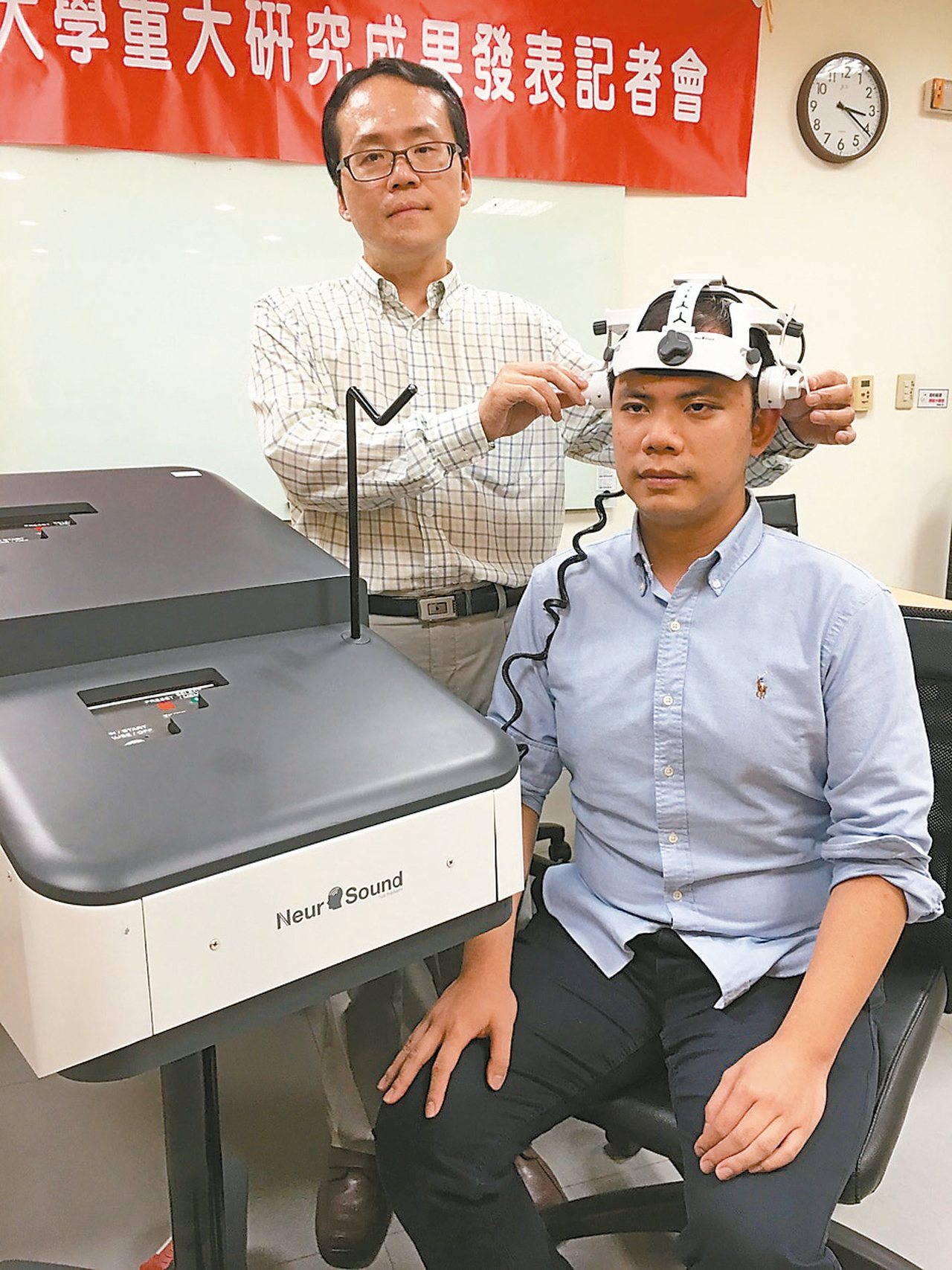 陽明大學教授楊逢羿(左)為模特兒戴上治療頭盔，示範如何使用「穿顱式超音波」改善失智症。