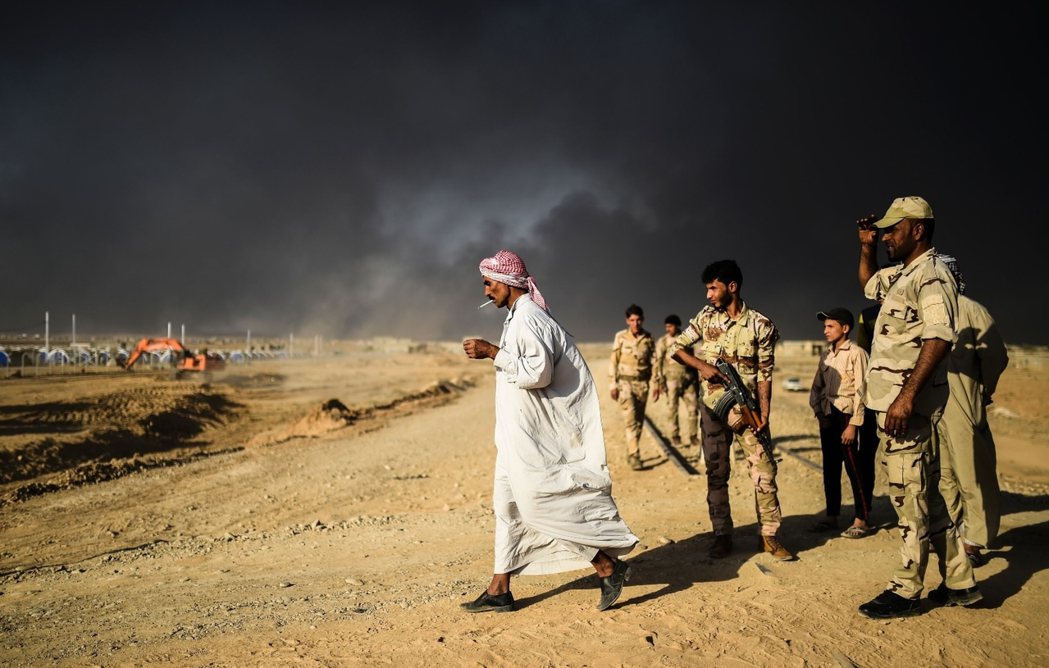 摩蘇爾南方的臨時難民營，附近遭ISIS縱火燃燒數月的凱亞拉油井，將伊拉克的天空染...