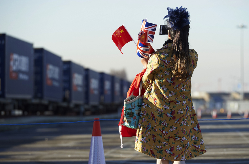 一名女子持英國及五星旗與火車拍照。(法新社) 陳韻涵