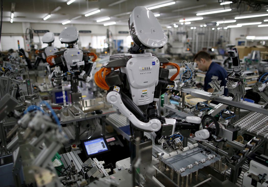 在日本的工廠裡，機器人與工人比肩工作。(路透)