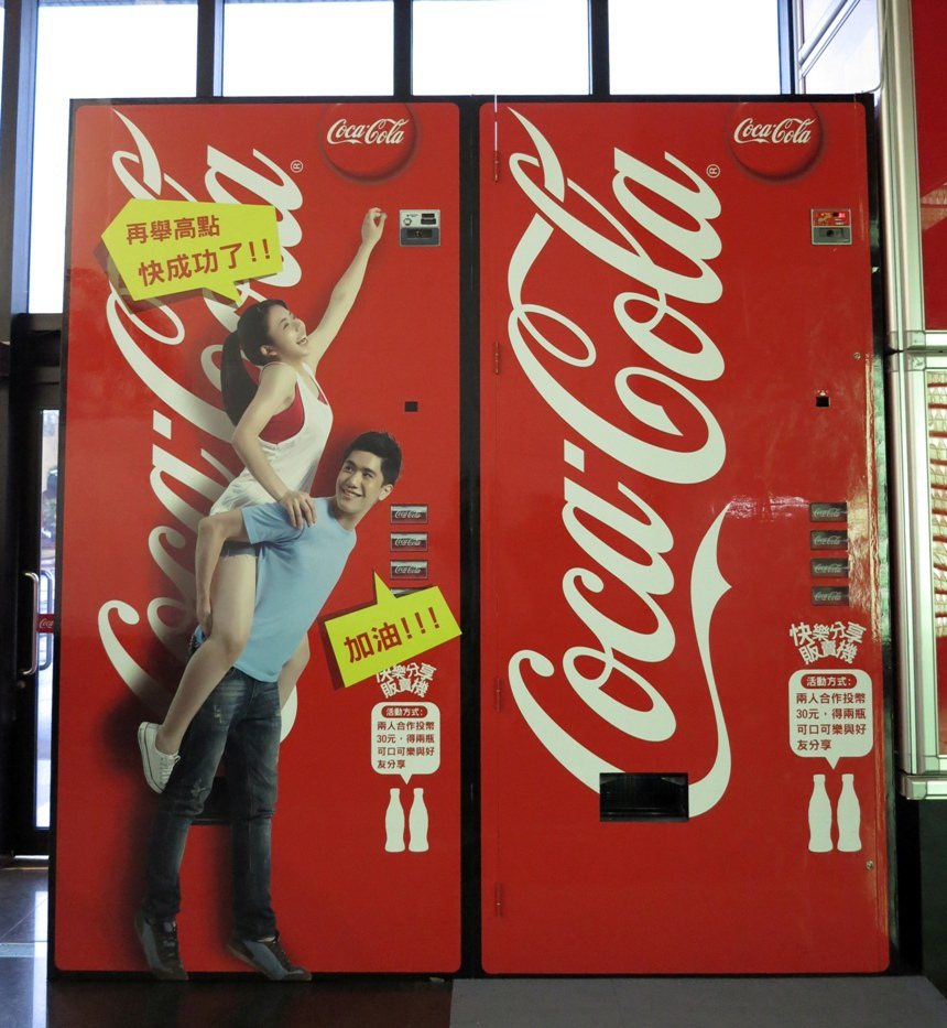 可口可樂博物館推出快樂分享販賣機，要像這樣背著才能投幣。記者賈寶楠／攝影