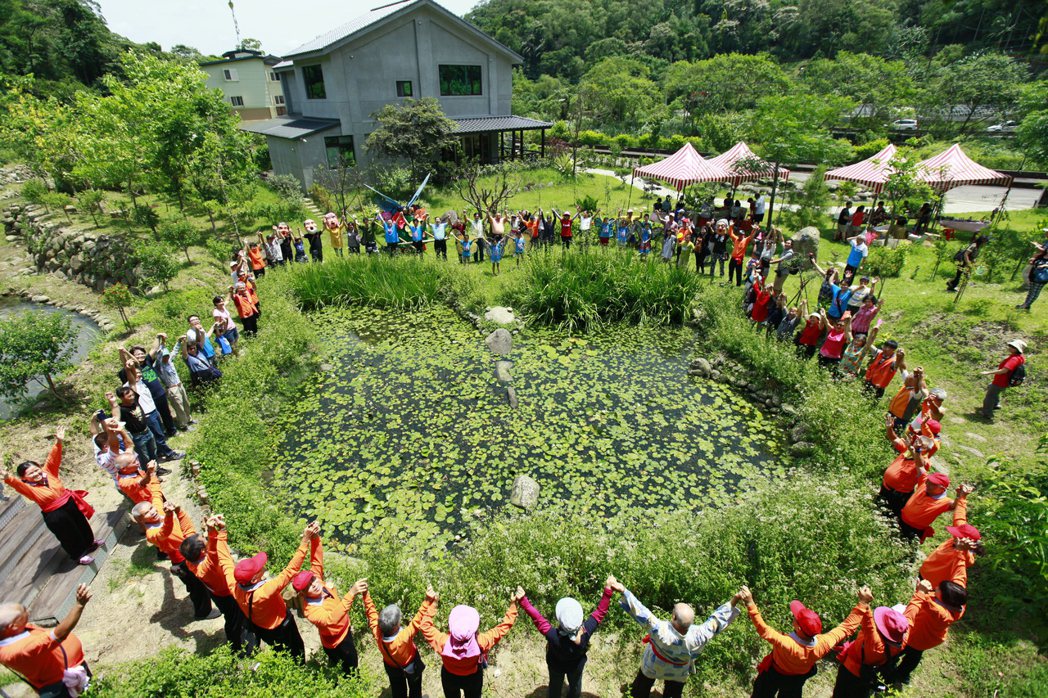社區居民圍繞著蝴蝶造型的蝴蝶池開心合影。圖／南外社區協會提供