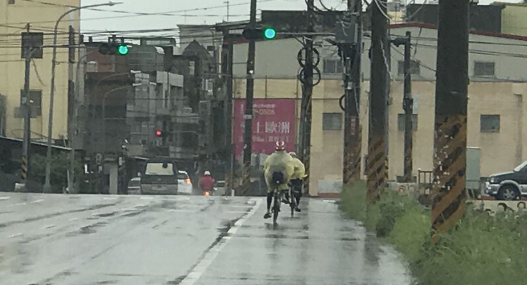 彰化縣鹿港鎮上午下起雨，單車騎士穿上雨衣冒雨騎車。記者林宛諭／攝影