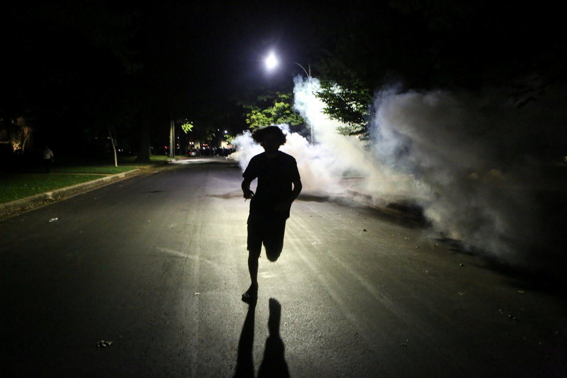 17日深夜，在美國密蘇里州聖路易市的街頭，一名示威抗議者正逃離警察的催淚瓦斯攻擊...