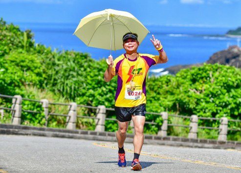 今年的火燒島全國馬拉松是歷屆最高溫，有選手熱得戴帽子還不夠，更撐傘跑。 (運動筆...