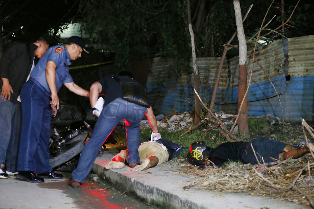 菲律賓警查看在掃毒行動中死亡的2名吸毒嫌犯。 （美聯社）