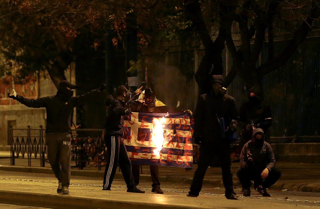 希臘抗議人士在一場示威活動中，焚燒希臘國旗洩憤。 （路透）