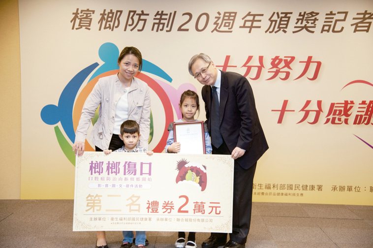 國健署署長王英偉（右起），頒獎給得主康茞芯，媽媽和弟弟一起上台領獎。